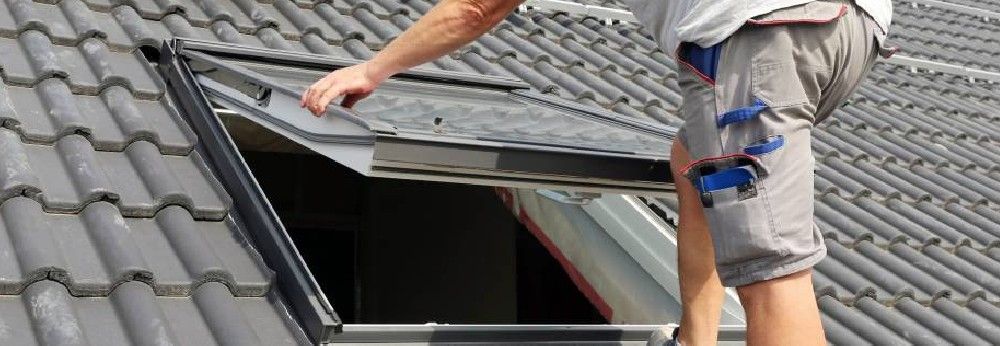 Mann baut Dachfenster ein 