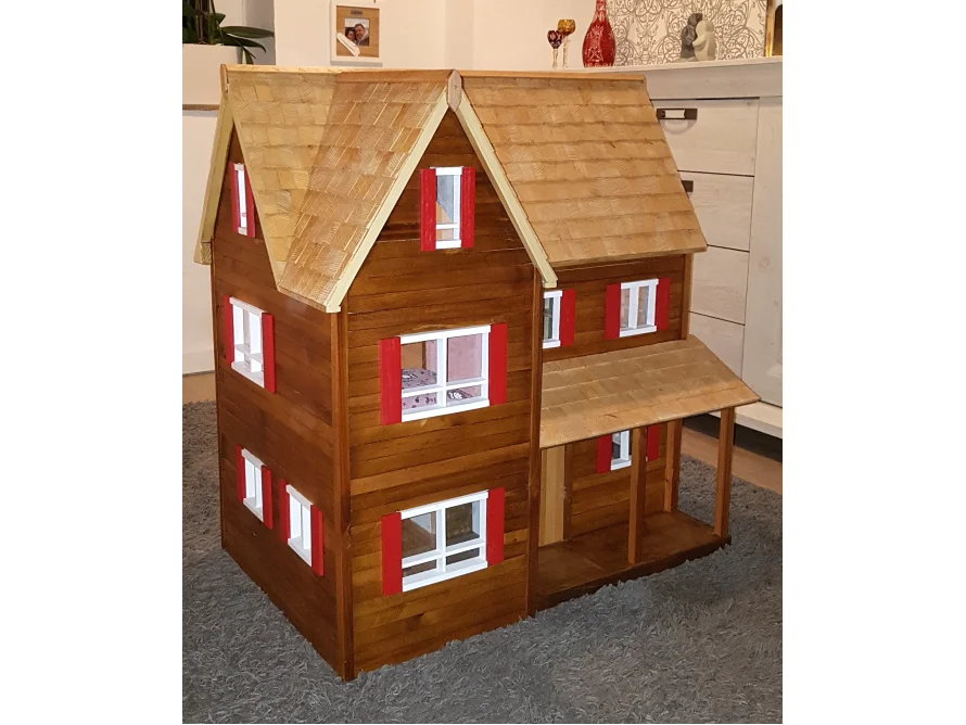 Ein großes hölzernes Puppenhaus mit roten Fensterläden.