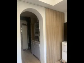 Eine Schiebetür aus hellem Holz vor einem gewölbten Durchgang