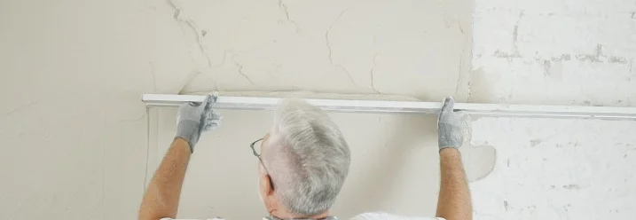 Person verputzt eine Wand mit Glättkelle.