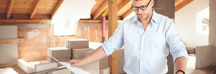 Person betrachtet Bauplan im Rohbau