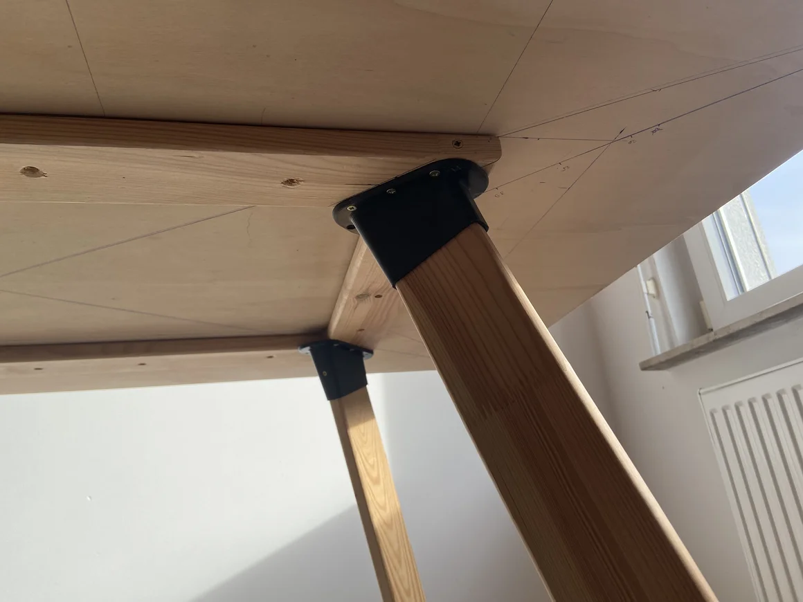 Angeschraubtes Tischbein an der Unterseite eines Holztisches.