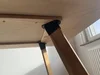 Angeschraubtes Tischbein an der Unterseite eines Holztisches.