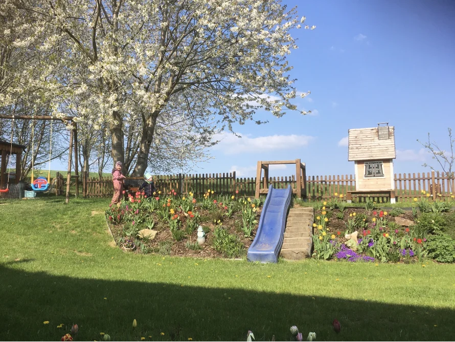 Garten mit Spielplatz und blühenden Bäumen