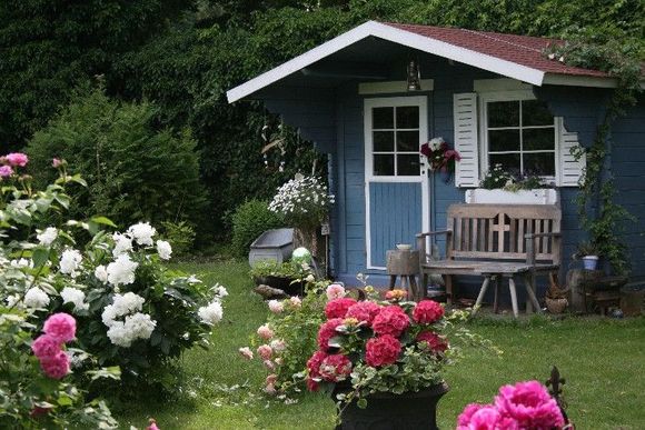 Ein klassisches Gartenhäuschen in einem bewachsenen Garten.