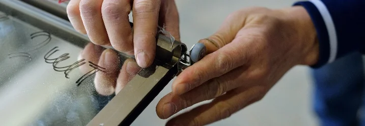 Hände befestigen eine Türrolle an einem Türrahmen.