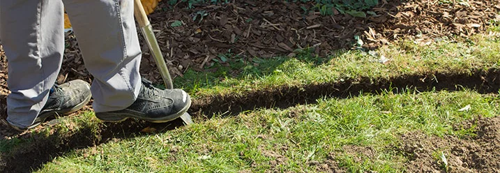 Person sticht Rasenkante mit Spaten ab