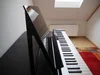 Ein schwarzes Digitalpiano steht in einem Raum.