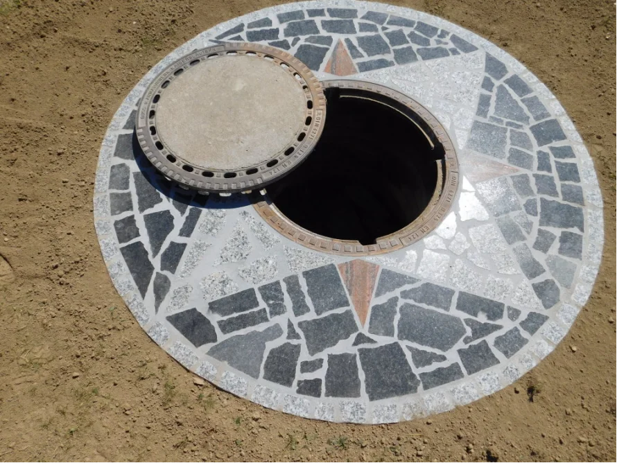 Offener Kanalisationsschacht mit Mosaikmuster