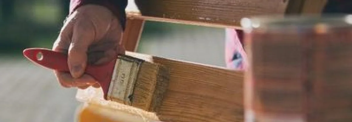 Person streicht Holzstuhl mit Pinsel