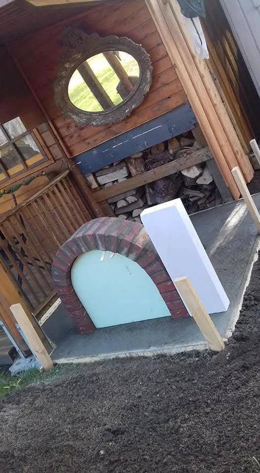 Bau eines gemauerten Pizzaofens auf einem Betonsockel im Garten.
