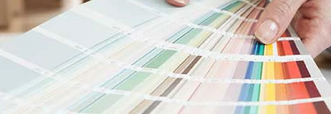 Hände halten einen Fächer mit Farbmustern.