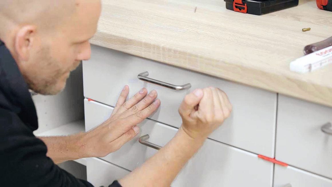 Die Front ist an der Schublade montiert und der Handwerker stellt die letzten Handgriffe fertig.