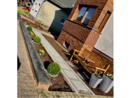 Gepflasterter Weg in einem Vorgarten mit Holzbank