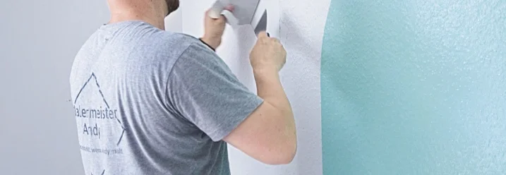 Person entfernt Tapete mit Spachtel