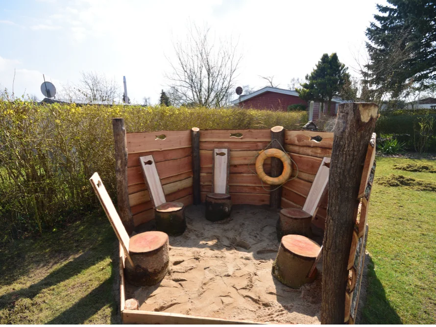 Spielbereich aus Holz mit Baumstämmen als Hocker