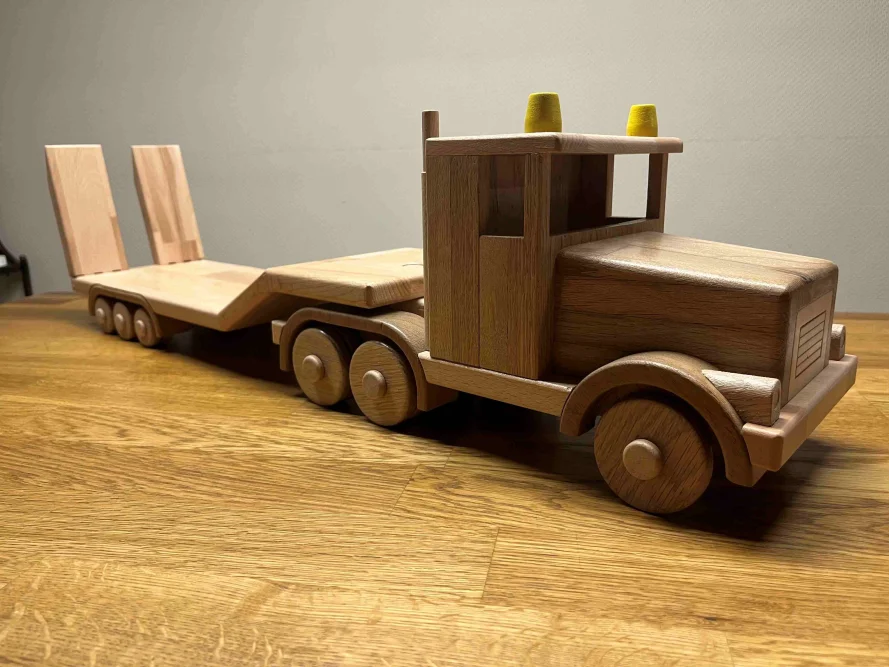 Ein Spielzeuglastwagen aus Holz mit Anhänger.