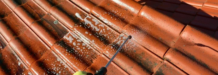 Person reinigt Dach mit Hochdruckreiniger