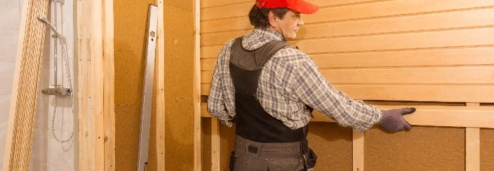 Person bringt Holzverkleidung an