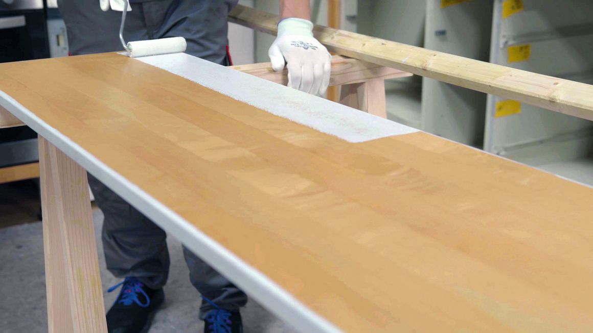 Mit einer kleinen Malerrolle wird die Küchenfront lackiert.
