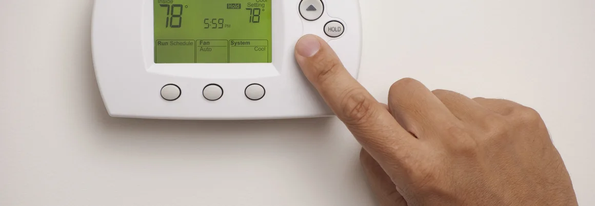 Hand stellt Thermostat ein