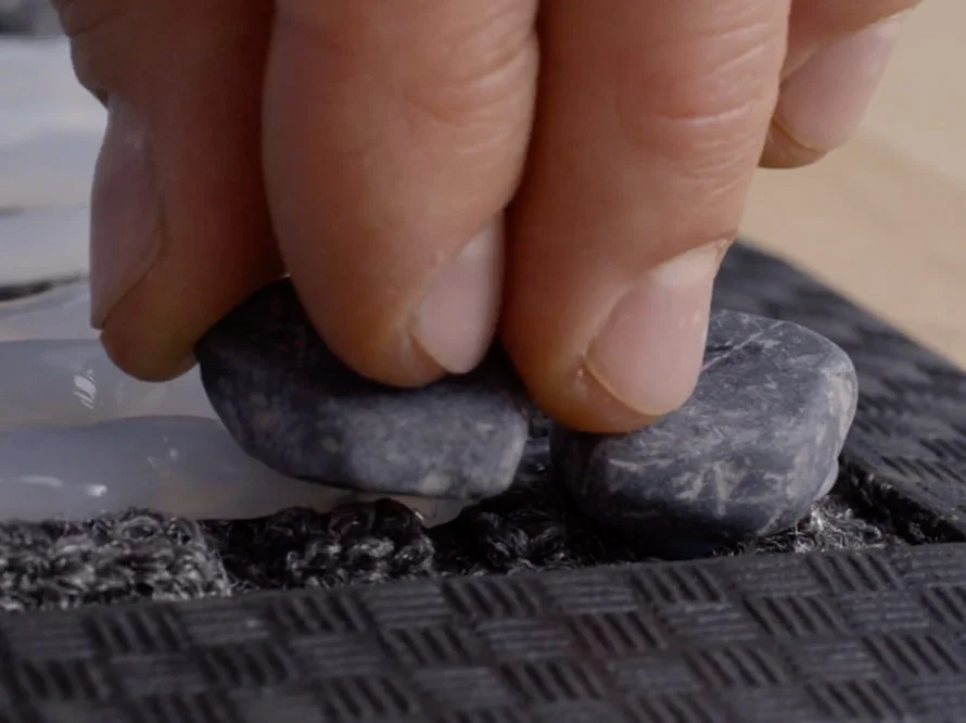 Hand platziert Steine auf einer Matte