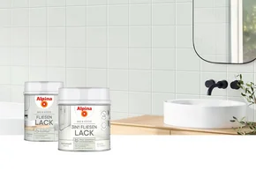 Zwei Farbdosen Fliesenlack vor Badezimmerfliesen.