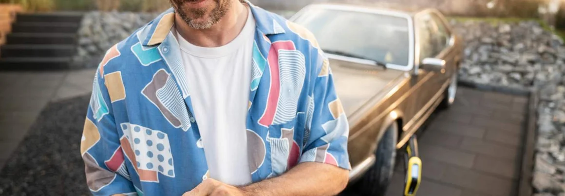 Person benutzt Smartphone neben Auto und Hochdruckreiniger