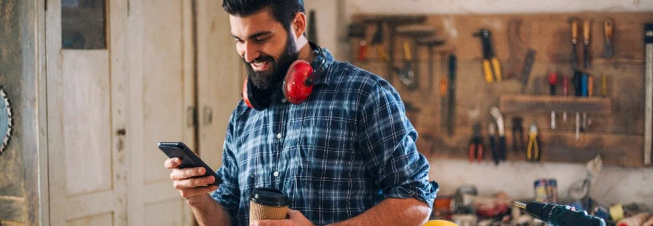 Person mit Smartphone in Werkstatt
