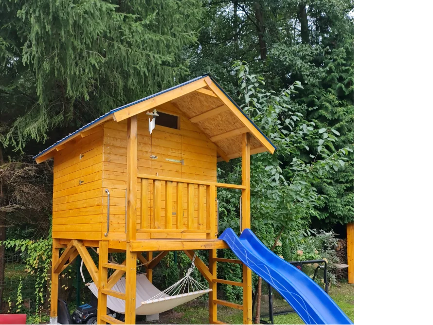 Hölzernes Spielhaus mit blauer Rutsche und Hängematte