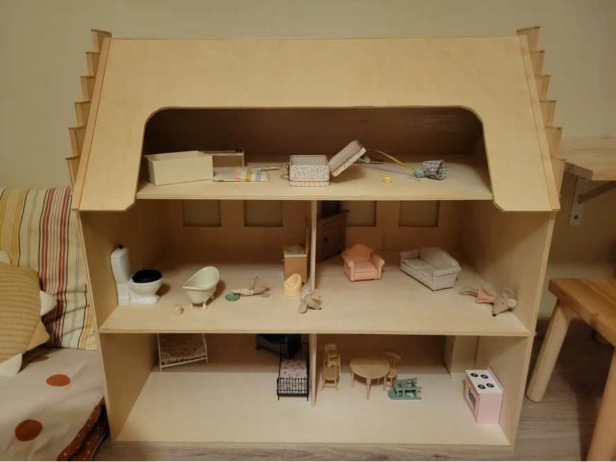 Ein unbemaltes Holzpuppenhaus mit drei Etagen.