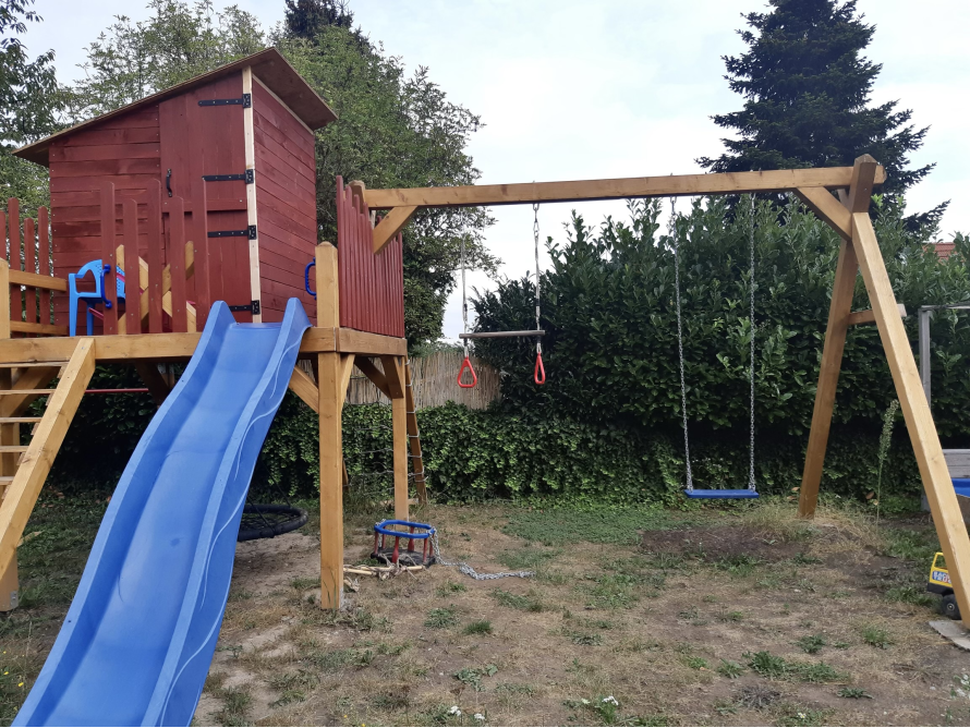 Hölzerner Spielplatz mit Rutsche und Schaukeln