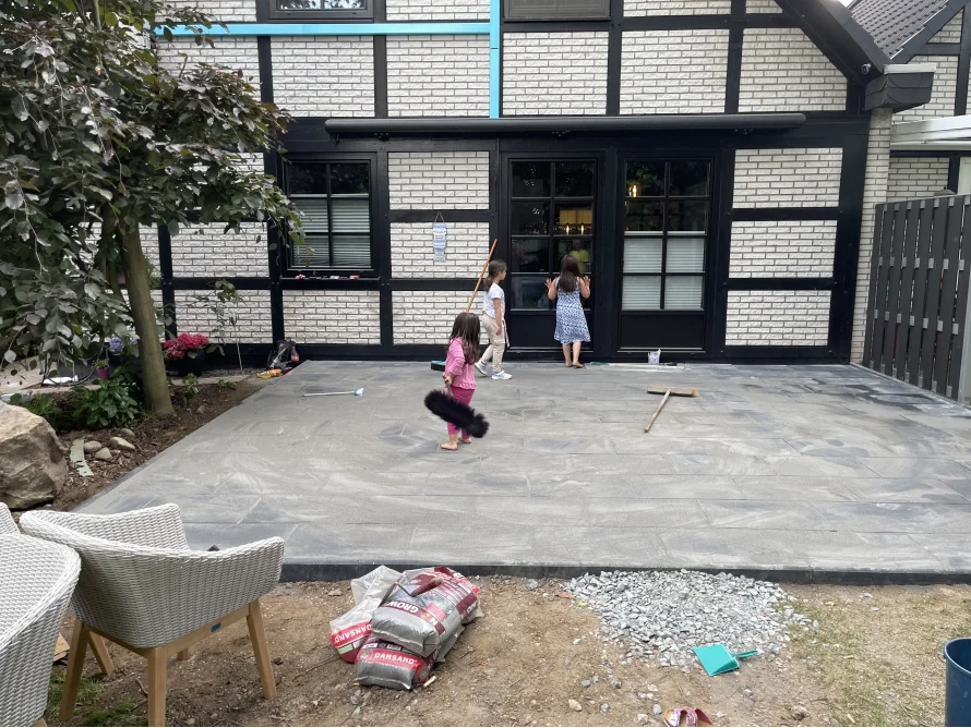 Drei Kinder auf neu verlegter Terrasse