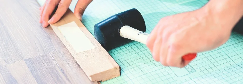 Person verlegt Laminat mit Gummihammer.