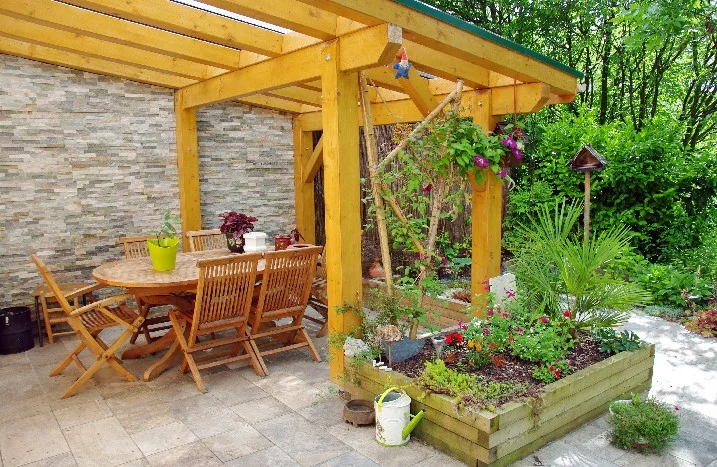 Holzpergola mit Gartenmöbeln und Blumen