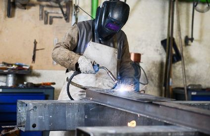 Mann schweißt in einer Werkstatt heißen Stahl mit GMAW Schweißer und Schutzausrüstung
