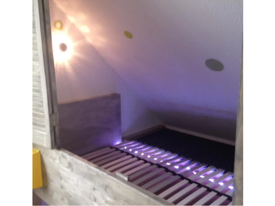 Ein Bettgestell aus hellem Holz unter einer Dachschräge.