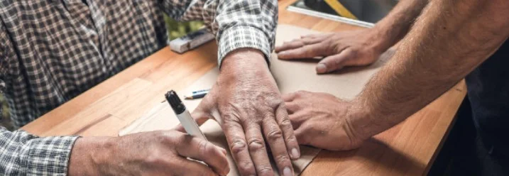 Zwei Personen zeichnen auf Holzplatte