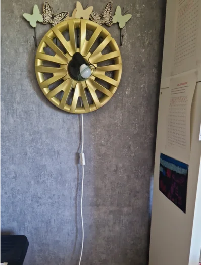 Wandlampe aus goldfarbener Radkappe