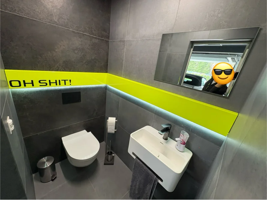 Moderne Toilette mit schwarzem und gelbem Fliesenspiegel