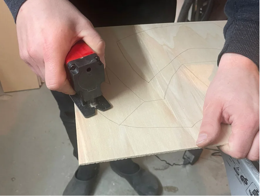 Person sägt Sperrholzplatte mit Stichsäge