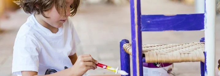 Kind streicht einen Holzstuhl