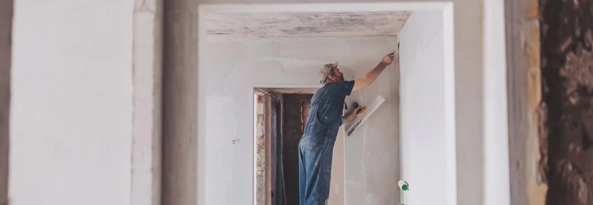 Bauarbeiter auf der Baustelle erneuert Gips von Innenwänden und Decken mit Schwimmer und Gips.