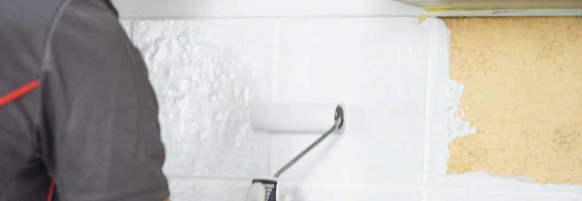 Person streicht Wand mit Farbrolle