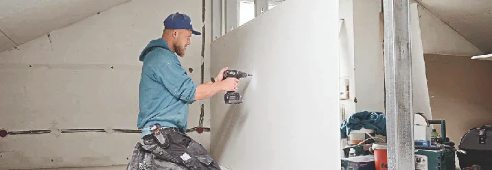 Person baut eine Wand mit einem Akkuschrauber.