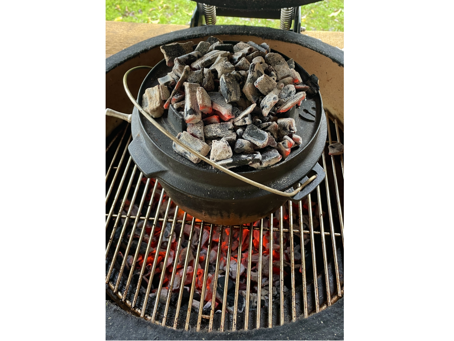 Gusseisentopf mit glühender Kohle auf einem Grill