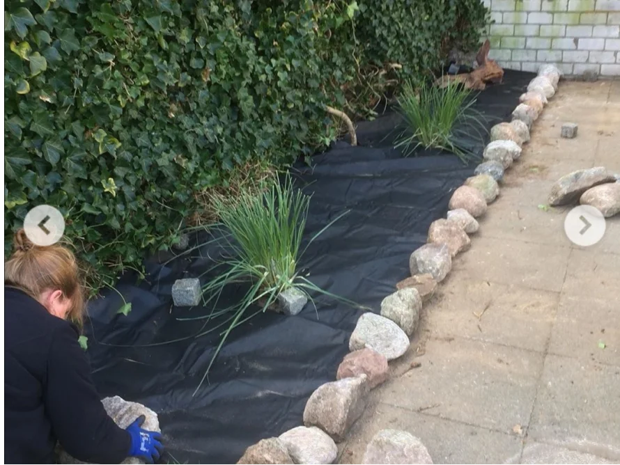 Person legt im Garten Unkrautvlies aus