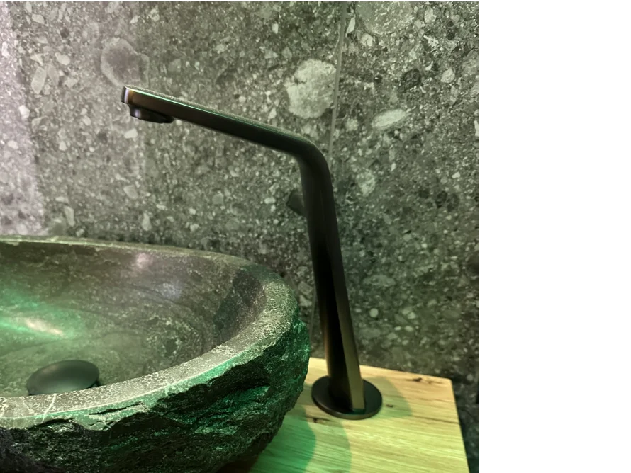 Ein moderner Wasserhahn über einem Waschbecken aus Stein.