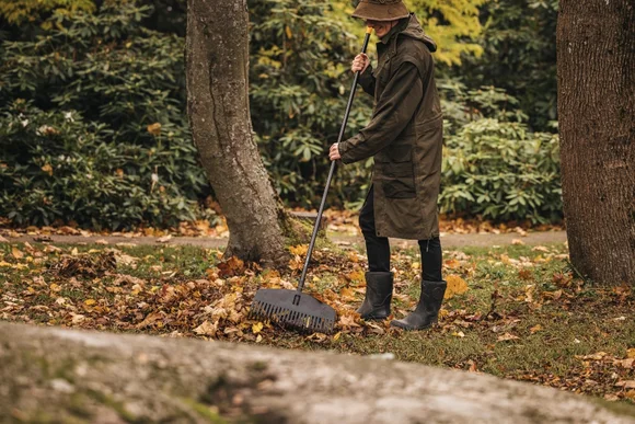 Person rechnet Laub mit Rechen zusammen