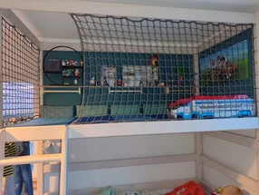 Hochbett mit gesicherter Spielebene und Spielzeug.